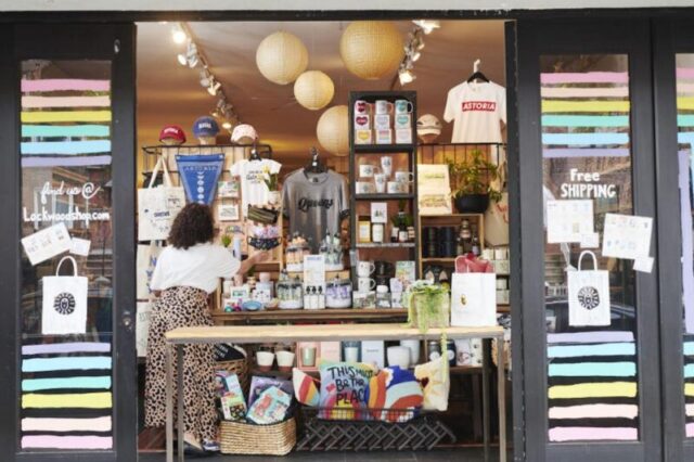 Сотрудник регулирует маски для лица, выставленные на продажу в открытом окне магазина Lockwood в районе Астория в боро Куинс, Нью-Йорк, США, в пятницу, 5 июня 2020 года. Для небольших бизнесов Нью-Йорка, которые почти полностью зависят от местных жителей, понедельник стал важным моментом для начала привлечения клиентов и доходов, которые они потеряли во время закрытия, что стало еще более рискованным с текущими социальными волнениями. Фотограф: Габби Джонс/Bloomberg через Getty Images