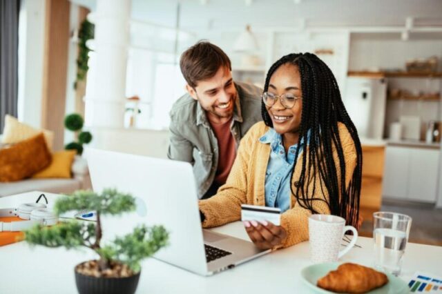 Пара дома, работающая на ноутбуке. Семья использует кредитную карту для онлайн-платежей.