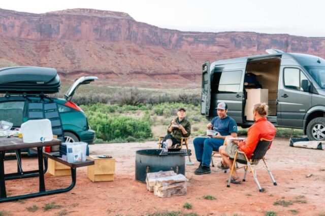 Друзья сидят вокруг костра с караваном на фоне