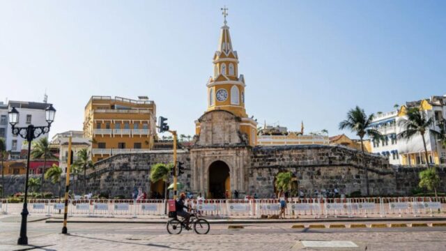 Картахена, Колумбия - 4 февраля 2024 г.: Исторический центр в солнечную погоду. Мужчина катается на велосипеде мимо Торре дель Релож