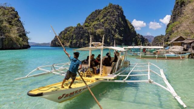 12 апреля 2018 года: лодочник управляет традиционной туристической лодкой-выносом на посадочной станции для озера Каянгам. 1073082074 RFC, Shutterstock, Азия, синий, лодка, лодки, Корон, направление, отдых, отпуск, остров, пейзаж, природа, океан, вынос, Палаван, рай, Филиппины, море, небо, лето, туризм, турист, туристы, традиционный, путешествие, тропический, отдых, вода, остров Корон, озеро Каянгам. Лодка, Мальчик, Ребенок, Шляпа, Земля, Мужчина, Природа, На улице, Человек, Море, Лето, Транспортное средство, Вода, Водный транспорт лодочник управляет традиционной лодкой-выносом на посадочной станции для озера Каянгам.