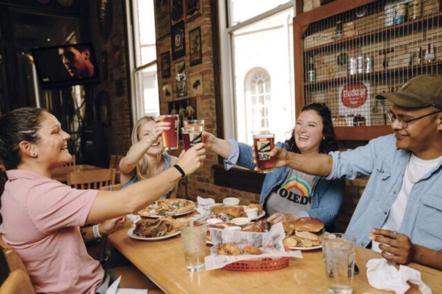 группа друзей, наслаждающихся закусками и пивом в Maumee Bay Brewing в Толедо, Огайо