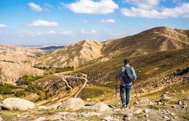 Путешествие в одиночку в горах. Мужчина, занимающийся пешим туризмом в горах при ясной погоде 1442159148 Лицензировано для Best in Travel 2024